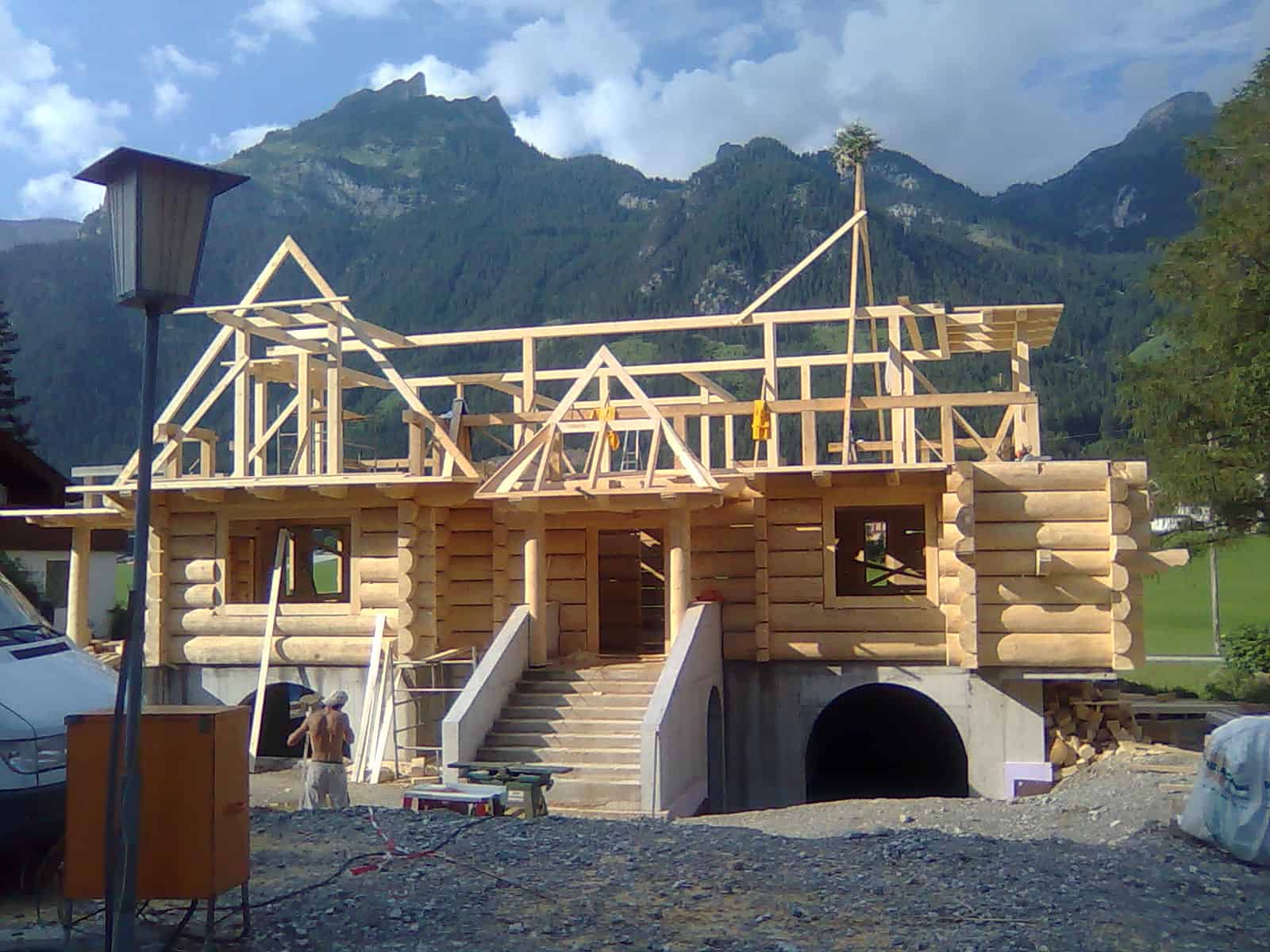 Blockhaus im Bau mit aufgesetztem Dachstuhl in den Bergen